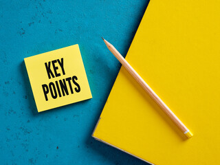 The word key points on yellow sticky note paper with a pencil and binder.