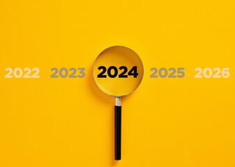 Magnifier glass magnifying the year 2024 among the previous and following years.