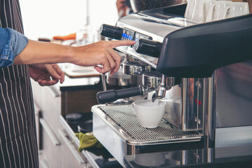 Close up hands coffee barista man make hot cup espresso shot from coffee machine. Cappuccino with...