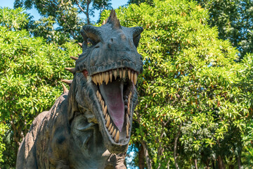 Fototapeta premium An angry predatory dinosaur in the green jungle screams and growls throughout the forest.