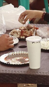 Two people eating pork lechon with their hands, a famous Filipino local delicacy 