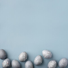 Festive Easter background. Gray-blue Easter eggs with stars on a blue table. Card with a place for...