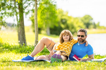 Fototapeta premium daddy and son relax in park. childhood school education. son with daddy bonding in summer. family education of daddy and son child. daddy inspire educational journey of his son kid. family day