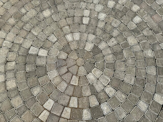 Natural grey cobbles or paving stone slab forming circular pattern for outdoor garden flooring finishes.