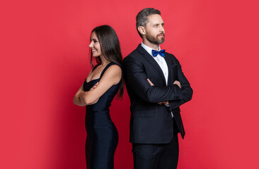 Woman and man at occasion date. Romantic love. Valentines day. Elegantly dressed couple. Formal man and woman. Couple is posing. Elegant couple in formal clothes isolated on red. Fashion style