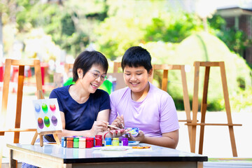 young cheerful teen student enjoy studying school art project with middle age asian teacher at school art club outdoors,female teacher helps teenage pupil painting in art class