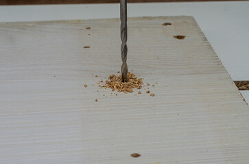 Drill drilled a hole in a wooden board with a drill. Close-up