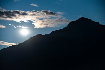 Silhouette of moutain range in a full moon night with clouds in the Italian Alps at lake Como