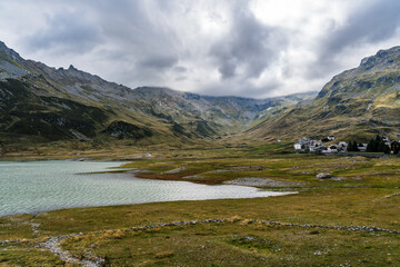 Fototapeta premium Reservoir lake in the Italian Alps near mountain pass Splügen with big mountain range and italian mountain village in the background