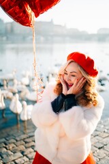 Obraz premium Woman with heart balloons on the river bank with swans in Prague