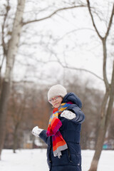 Fototapeta na wymiar A girl plays with snowballs in a winter park