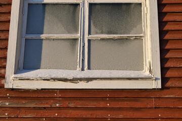 Old wooden building window with frozen glass