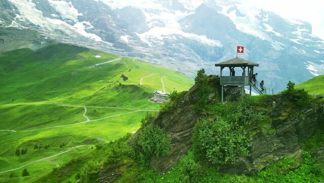 Drone Switzerland 4k. Kleine Scheidegg to Jungfraujoch. Swiss flag, hikers in Swiss Alps. Summer tourism destination.