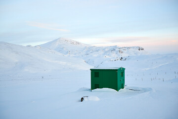 Snow proof metal shed cabin by snowy mountains in winter