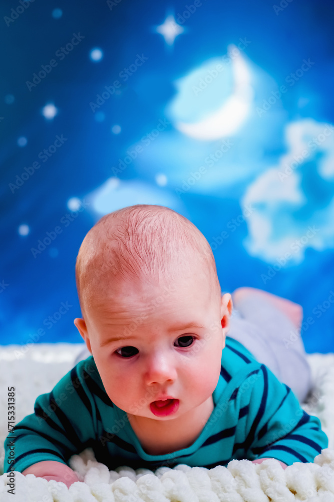 Wall mural time to sleep, carefree dreams concept. funny portrait of baby boy 4 months old lies on the bed agai