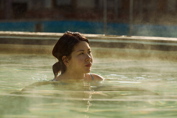 A young Asian girl, 25-30 years old, bathes in a hot springs poo