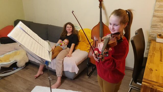 home rehearsal. girls play violin and double bass. Little first viewer