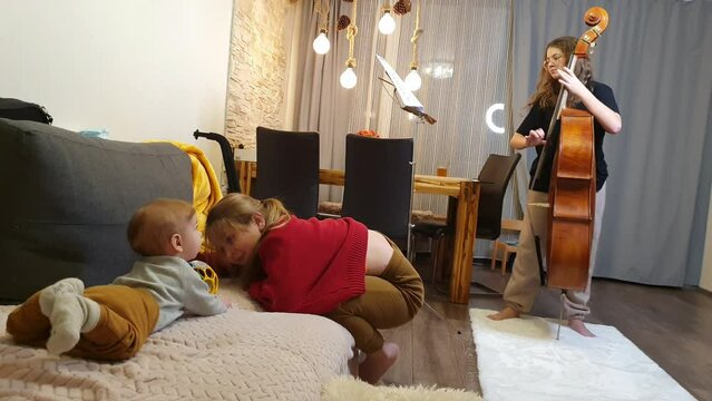 home rehearsal. girls play violin and double bass. Little first viewer