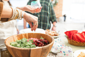 Woman's Hands Preparing Salad in Wood Bowl