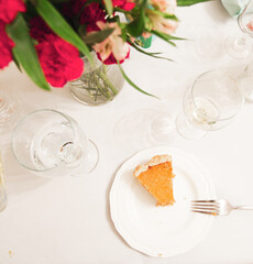 Pumpkin Pie on White Plate with Bite Taken, Flowers on Table