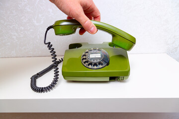 A hand picks up the receiver of Nostalgic retro telephones