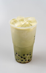 Closeup of a cup of delicious cold green bubble tea with boba and ice on top