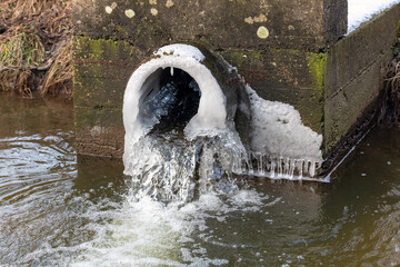 A stream of water flowing from a drainage pipe in a canal