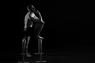 Male gymnast performing handstand on parallel bars, studio shot