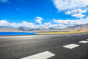 Asphalt road and lake with mountain natural landscape under blue sky