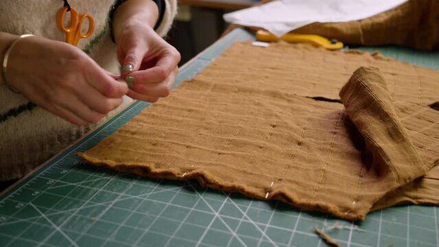 Fashion designer seamstress pinning together fabric cut from a sewing pattern template.