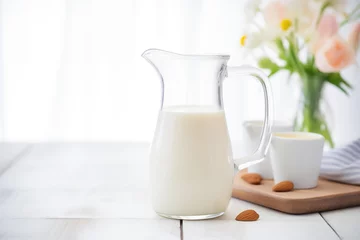 Fotobehang almond milk in a clear pitcher with whole almonds arranged around © primopiano