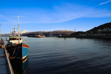 Fototapeta premium small harbor with a fishing boat in Norway with mountains in the background