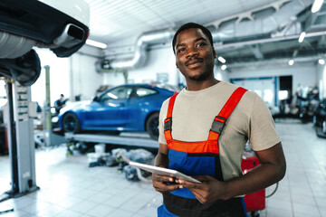 Young African auto mechanic using digital tablet in a car service