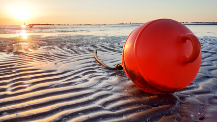 Orange nautical signal buoy on the beach of Riccione at dawn