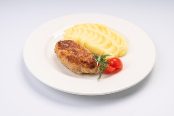 Dinner. Fried cutlet in mashed potatoes on a white plate and a white background