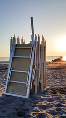 deckchairs piled closed on the beach at dawn