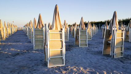 beautiful sunrise with sun reflection on cesenatio riccione rimini beach with open umbrellas