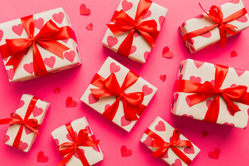 Top view photo of valentine day decorations gift box with red ribbon bow on colored background....