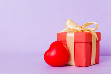 gift box with red bow and red heart on colored background. Perspective view. Flat lay