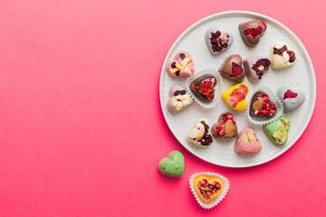 Plate with different chocolate on colored background. Assortment of fine chocolates top view vith copy space Health and obesity concept