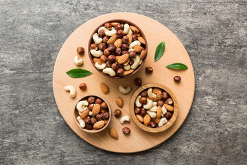 Assortment of nuts in wooden bowl on colored table. Cashew, hazelnuts, walnuts, almonds. Mix of nuts Top view with copy space