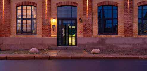 The façade of the historic building together with the granite pavement illuminated by the light of...
