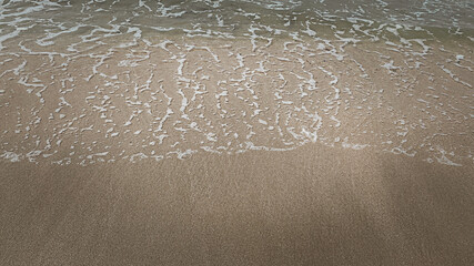 Soft waves of the blue ocean on the sandy beach. Selective focus background.Summer with turquoise wave in tropical beach. Soft waves with foam of blue ocean on the sandy beach.