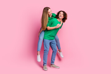 Full body photo of funny smiling brunet curly hair teen guy holding hands happy girl ride piggyback...