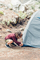 Cute boy setting up tourist tent. Summer travel, camping and hiking concept. Eco tourism.