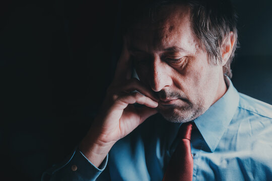 Worried depressed overworked businessman late at night, low key