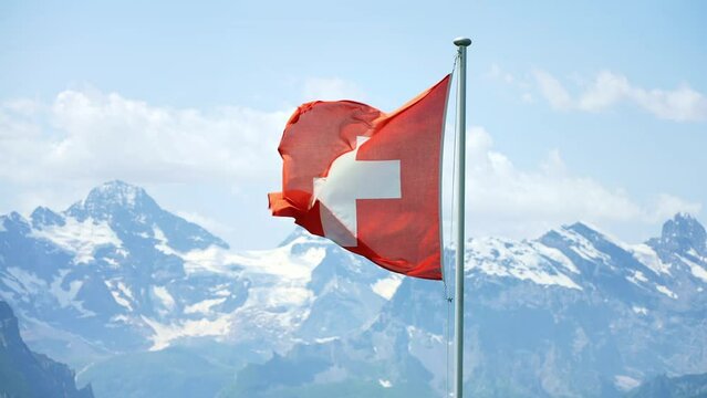 Swiss flag in Swiss Alps, tourists look at Jungfrau mountain on Mannlichen viewpoint, Bernese Oberland in Switzerland.