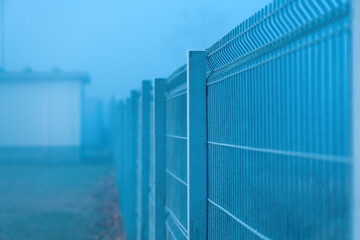 Steel metal fencing in foggy winter morning