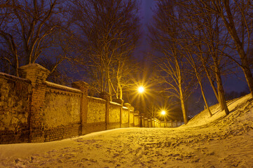 Zimowy park wieczorową porą, śnieg i stary mur - obrazy, fototapety, plakaty