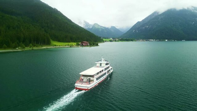 Tour boat on Achen Lake Achensee in Austrian Alps. Pertisau village popular tourist sightseeing destination in Tyrol region. Drone aerial view 
